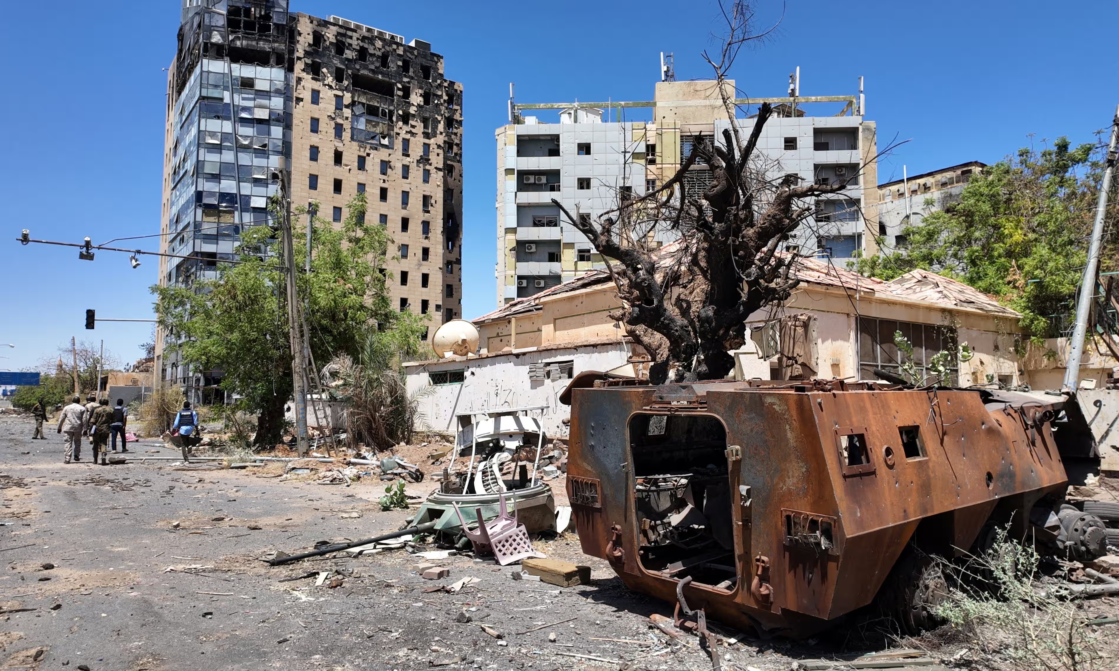 Members of the Sudanese army walk past a destroyed military vehicle and bombed buildings in Khartoum. Photograph: El Tayeb Siddig/Reuters